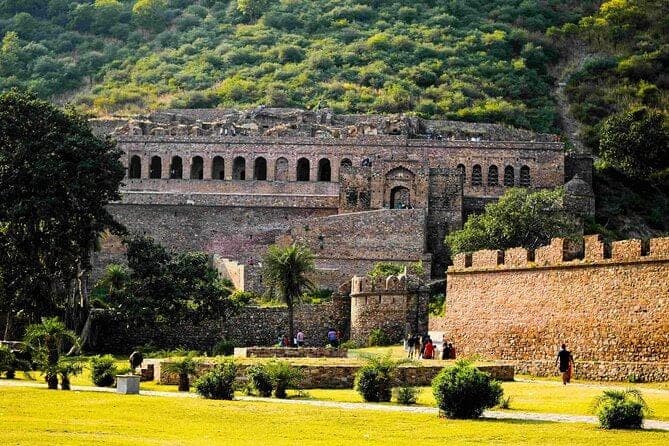 The roofless sandstone ruins of Bhangarh Fort stepping up a dry hillside.